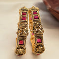 Ornate gold earrings with red gemstones on a light background