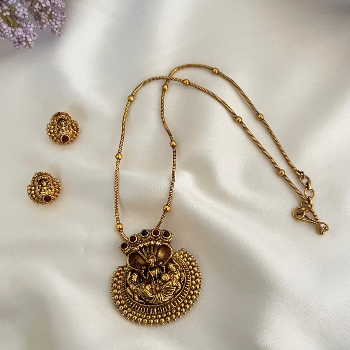 Gold necklace and earrings on a white fabric background